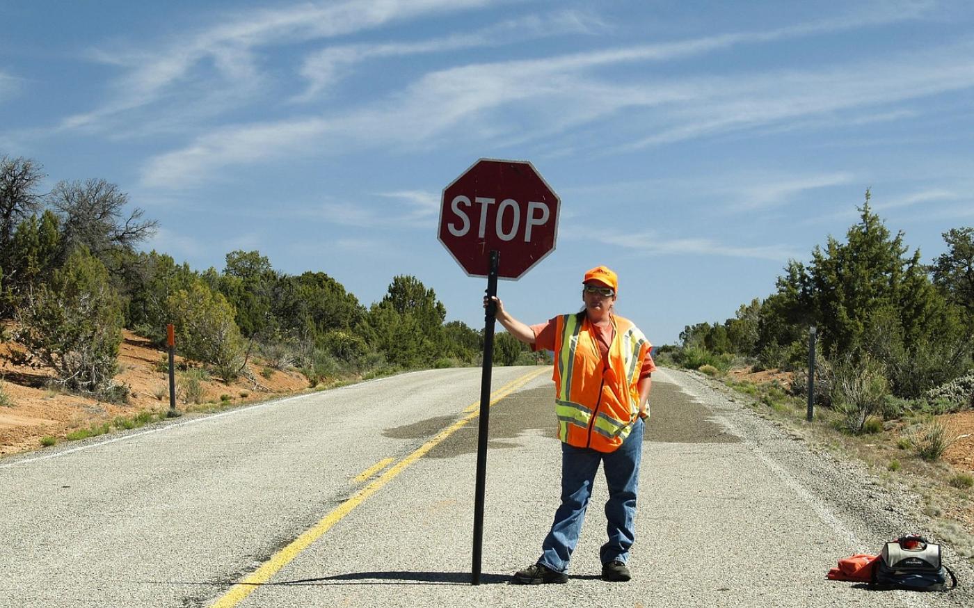 a construction worker standing on a road holding a stop sign